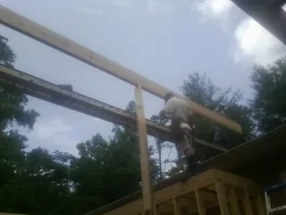 Carpenter setting a ridge beam over a new addition frame — Ice Dam Removal by Roofing Brothers in Lindale