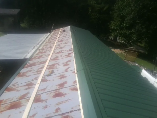 Old rusted panels beside newly installed green metal roofing — Wind Damage Roof Repair by Roofing Brothers in Lindale