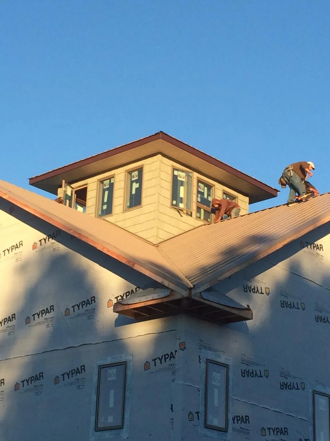 Roofers working around a rooftop cupola on a new metal roof at sunset — Roof Waterproofing in Lindale by Roofing Brothers